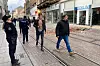 Bildet er av folk som går i en gate i Zagreb. Det er rester av vegg og tak på siden av gaten. En fra politiet snakker i telefonen mens hun ser opp på taket av en bygning.