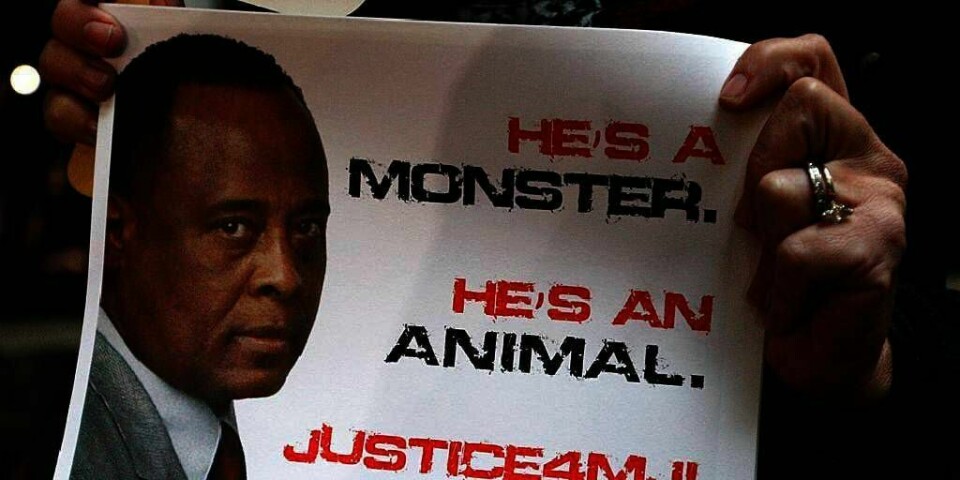 ANKLAGET: «Han er et monster. Han er et dyr. Rettferdighet for Michael Jackson», står det på plakaten med bilde av legen Conrad Murray. Mange fans var samlet utenfor rettssalen der saken mot legen startet tirsdag. De vil vite hva som skjedde da Jackson døde.