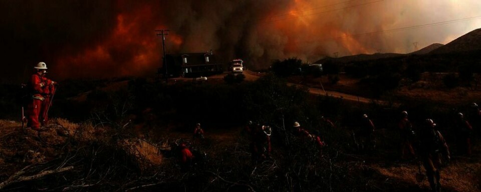 BRANN: Flammene truer et hus i California. Brannmenn forsøker å slukke brannene.