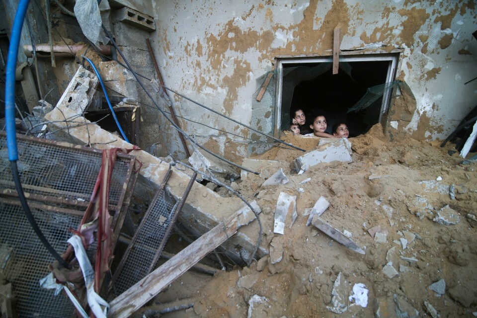 KRIG: Barn fra Palestina ser på et bygg som er ødelagt etter rakettangrep fra Israel. Palestinske barn ser gjennom vinduet i en ødelagt bygning i Rafah på Gazastripen. Foto: Hatem Ali / AP / NTB