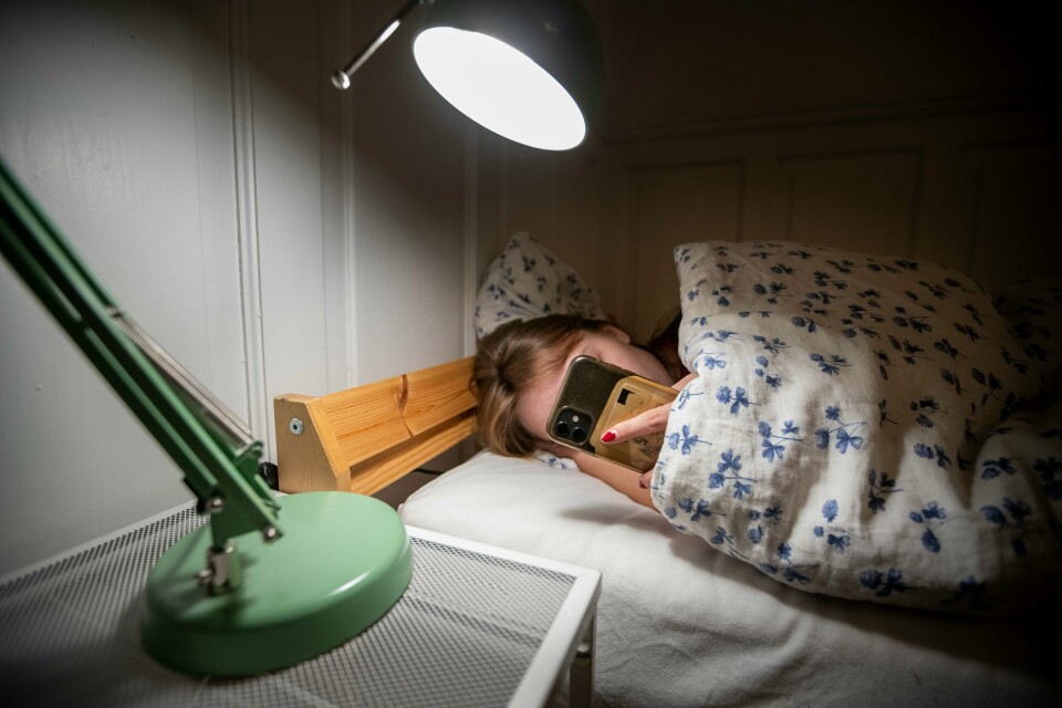 SLUMRING: Lar du alarmen ringe flere ganger før du står opp? Det trenger ikke være negativt, ifølge svensk studie. Bildet viser en kvinne som scroller på en mobil i senga.
