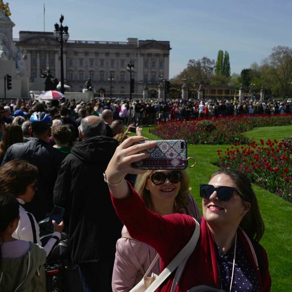 KRONING: Kong Charles skal krones lørdag. Turister fra hele verden er i London for å se på. Bildet viser turister foran Buckingham Palace i London.