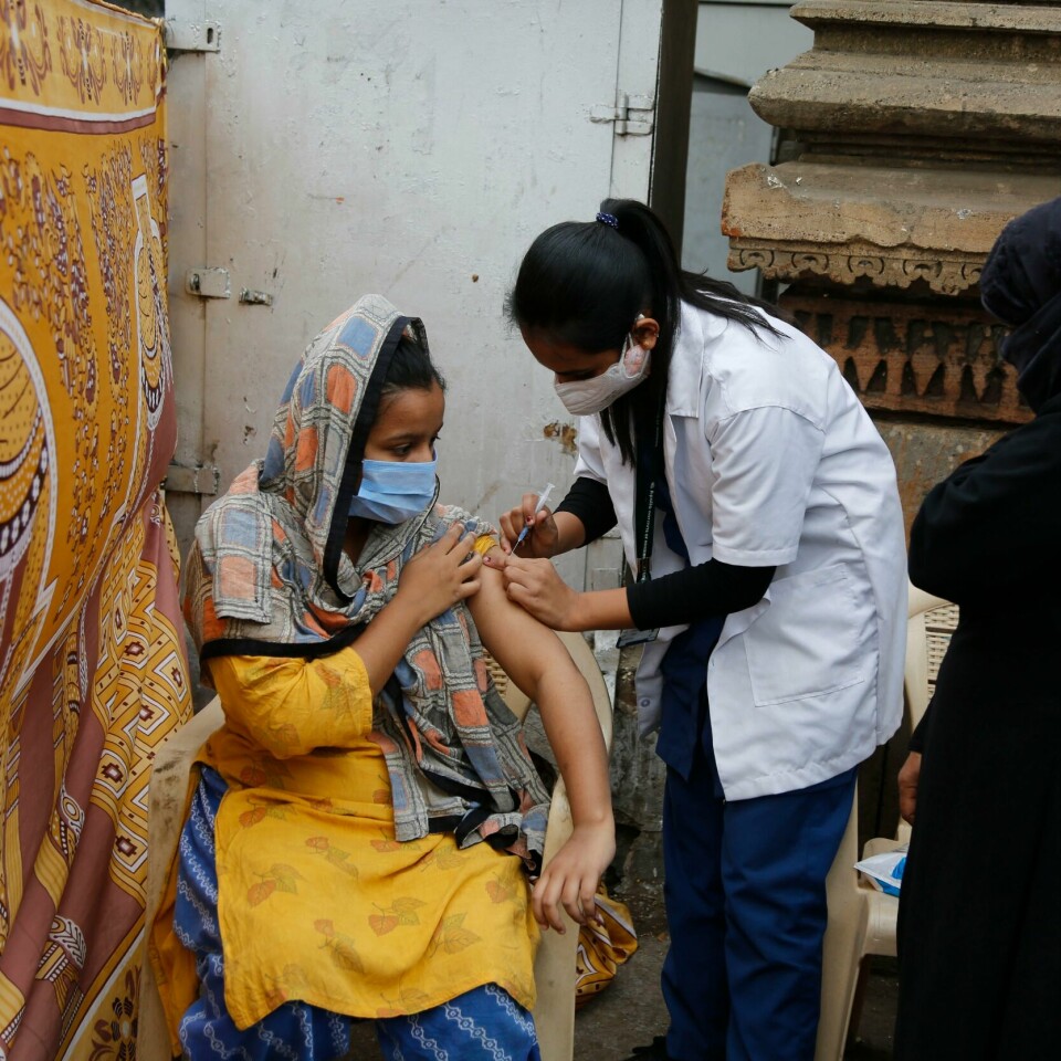 INDIA: En ung indisk kvinne får vaksine. 44 prosent av landets befolkning har nå fått to vaksinedoser. En kvinne blir vaksinert i Ahmedabad i India torsdag. Foto: Ajit Solanki / AP / NTB