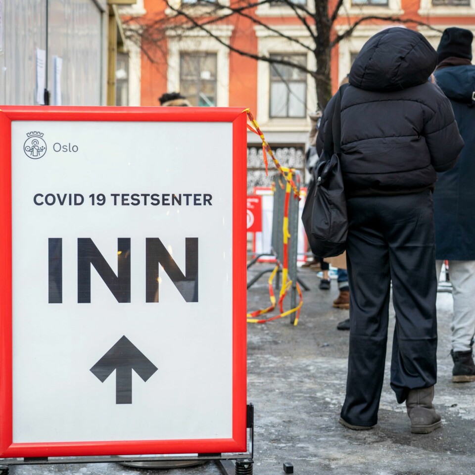 FLERE: De siste ukene har flere fått vite at de er smittet med korona. Bildet er av folk som står i kø for å få testet seg for korona. Det er is på bakken. Til venstre for dem er det et skilt med pil framover som viser til et senter der folk kan teste seg for smitte. Foto: Ole Berg-Rusten / NTB