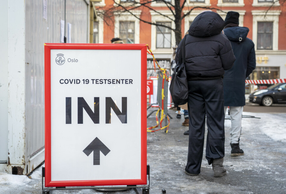 SMITTE: Mange har blitt smittet av korona i Norge den siste tiden. Bildet er av folk som står i kø for å få testet seg for korona. Det er is på bakken. Til venstre for dem er det et skilt med pil framover som viser til et senter der folk kan teste seg for smitte. Foto: Ole Berg-Rusten / NTB