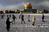 Bildet viser palestinere som leker i snøen ved Klippedomen i Jerusalem. Foto: Mahmoud Illean / AP / NTB