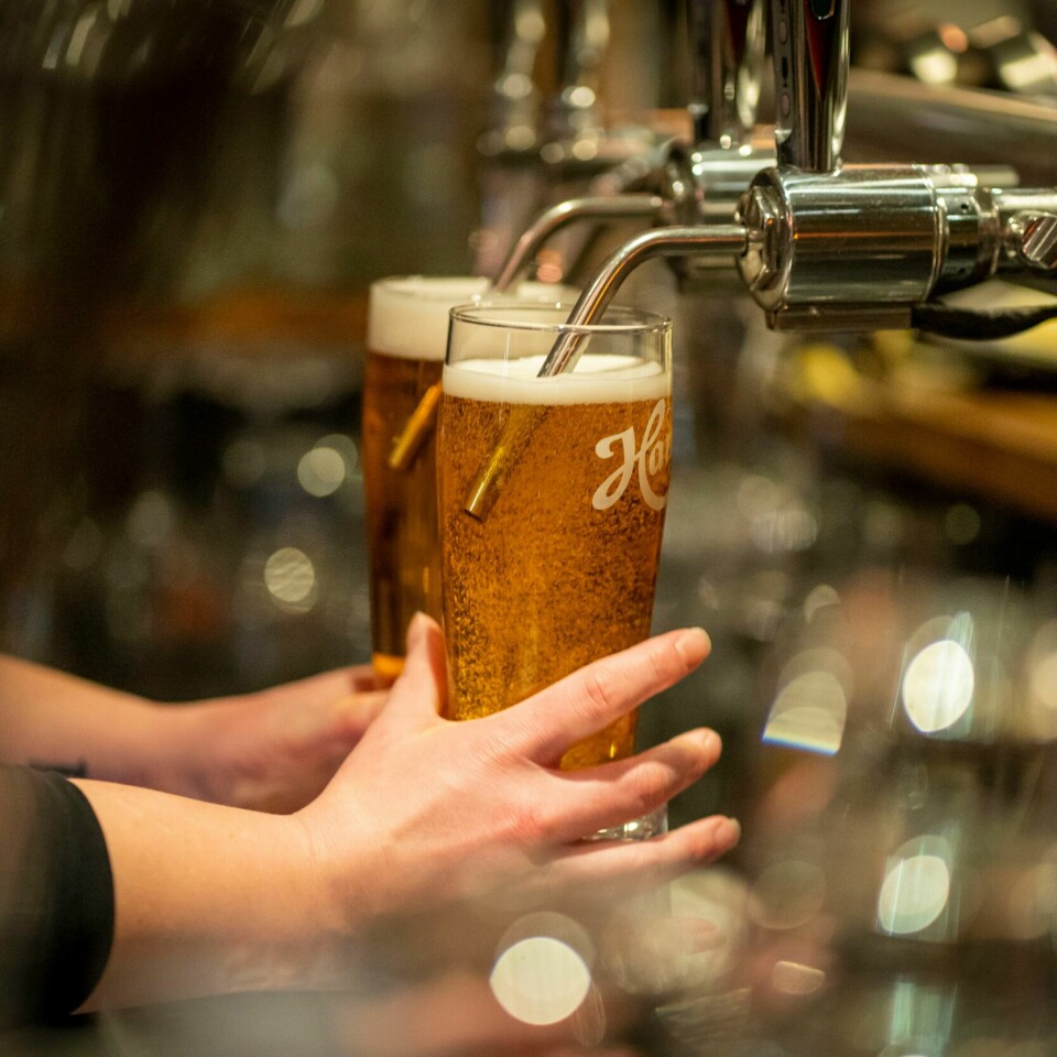 ALKOHOL: Folk kan drikke alkohol som vanlig på utesteder. Men de må fortsatt holde avstand. Bildet viser noen som tapper øl. Foto: Heiko Junge / NTB