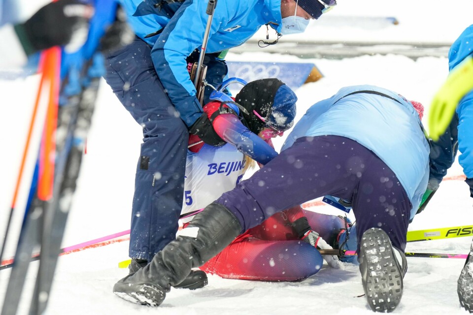 KOLLAPS: Ingrid Landmark Tandrevold kollapset. Det skjedde under jaktstarten søndag. Hun må dra hjem fra OL. Bildet viser skiskytter Ingrid Landmark Tandrevold som måtte støttes bort fra målområdet under OL. Foto: Heiko Junge / NTB