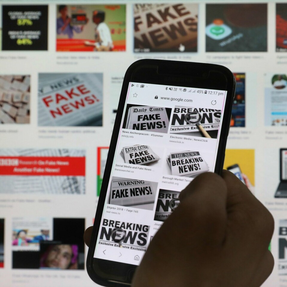 NYHETER: Forskere i Norge skal forske på falske nyheter og misvisende informasjon. Illustrasjons-foto. Bildet viser plakater der det står fake news og en person som scroller på en telefon.