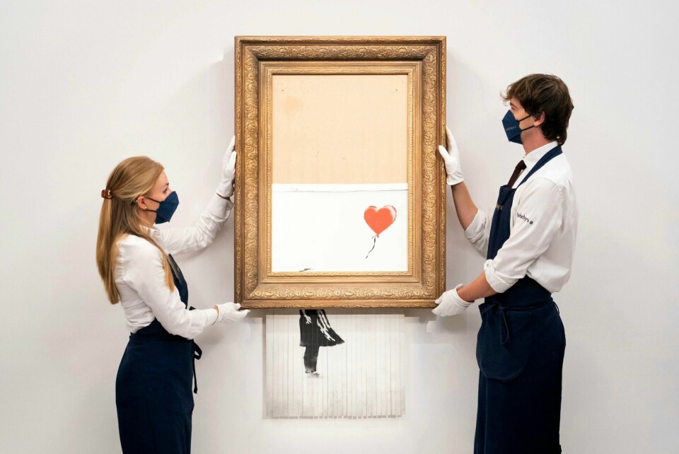 KUNST: Et av Baksys mest kjente verk er jenta med hjerteballongen. Her blir bildet hans makulert på et museum. Det delvis ødelagte verket fra artisten Banksy selges igjen, under det nye navnet «Love is in the Bin». Foto: Dominic Lipinski / PA / AP / NTB