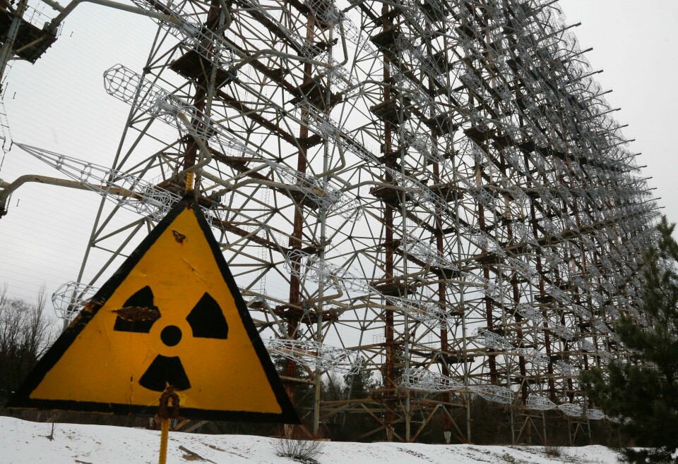 STRÅLING: Bildet er tatt i Tsjernobyl. Skiltet advarer mot radioaktiv stråling. Bak skiltet skal være et gammel radar-system laget av gamle Sovjetunionen. Det skal ha blitt brukt til å forsvare seg mot missiler. Skilt med faretegn på stråling.