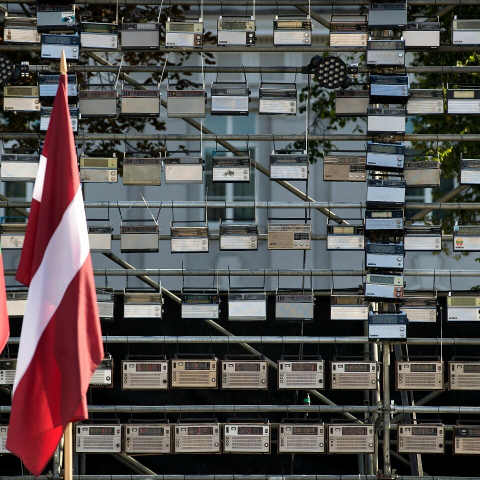PROTEST: Estland, Litauen og Latvia var alle del av Sovjetunionen. I 1989 fikk folk beskjed på radio om å lage en lenke av folk for å protestere for uavhengighet. Nå mener flere at den er truet. Fredag utviste landene til sammen ti diplomater fra Russland. Bildet er av det estiske, litauiske og latviske flagget. De henger foran en kunstutstilling med radioer. Illustrasjonsfoto: Mindaugas Kulbis / AP / NTB
