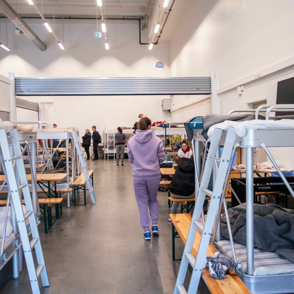 KRAV: Det er egne krav til bygg der det skal bo flyktninger. Gjensidige er usikre på om det er gjort nok ved alle byggene der det skal bo ukrainske flyktninger. Bildet er av en jente i joggedress som går mellom køyesenger på det nasjonale mottakssenteret i Råde. Det sitter folk ved bord i bakgrunnen. Foto: Javad Parsa / NTB