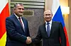 Bildet er av Anatoly Bibilov og Vladimir Putin. De tar hverandre i hendene mens de står foran hvert sitt flagg. Et sør-ossetisk, og et russisk. Bildet er fra 2017. Arkivfoto: van Sekretarev / AP / NTB