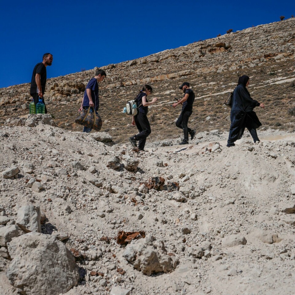 PÅ FLUKT: Tusenvis av mennesker har flyktet fra Libanon til Syria. Det skaper nye problemer i Syria, advarer Flyktninghjelpen. Bildet viser flyktninger på vei fra Libanon til Syria. Foto: Hassan Ammar / AP / NTB