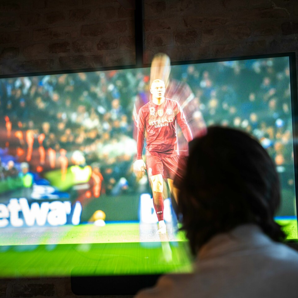 UNDERHOLDNING: Mange unge i Norge har ingen kvaler med å bruke ulovlige IPTV-tjenester for å spare penger. Illustrasjon av person som ser på fotball på TV.