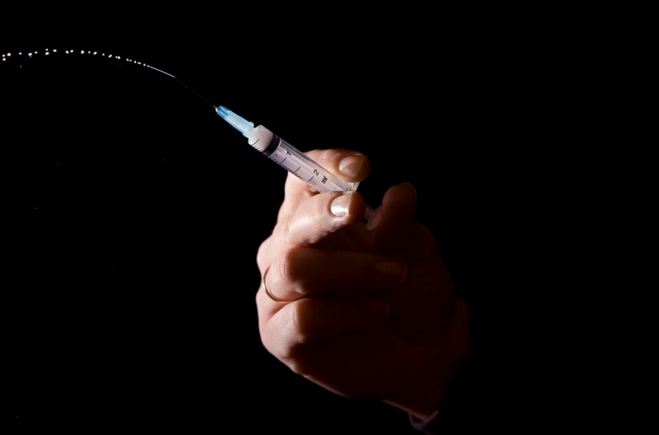 VAKSINE: Færre har fått hjernehinnebetennelse og blodforgiftning siden barn begynte å få vaksinen mot pneumokokksykdom. Illustrasjonsfoto av hånd med sprøyte mot mørk bakgrunn.