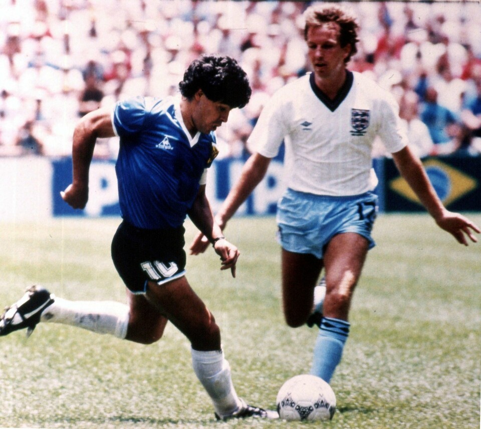 HISTORISK: Diego Maradona skåret det beste målet i forrige århundre. Nå skal drakta han brukte i kampen bli solgt. Bildet er av Diego Maradona som utfordrer Trevor Steven på en fotballbane. Maradona har på en blå argentinsk drakt. Steven har på en hvit engelsk. Foto: AP / NTB
