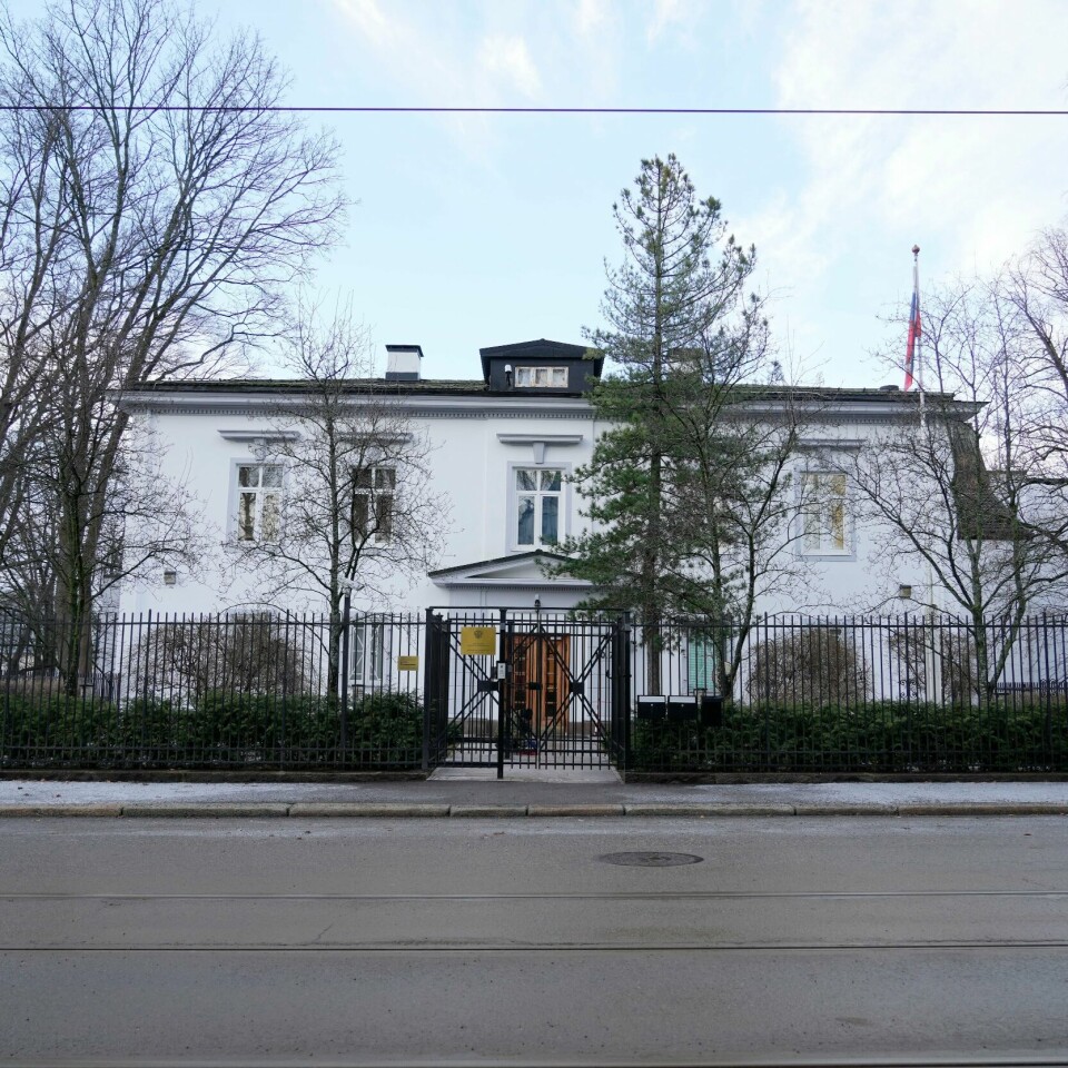 UTVIST: Tre av de ansatte på Russlands ambassade har fått vite at de er uønsket i Norge. De er utvist, og må reise hjem til Russland. Bildet er av den russiske ambassaden i Oslo. Bildet er tatt fra andre siden av gaten. Bygget er to etasjer høyt, har hvite vegger og sort tak. Bildet er fra i vinter. Det er mange løvtrær uten blader på bildet. Det russiske flagget henger rett ned, siden det er vindstille.Foto: Heiko Junge / NTB