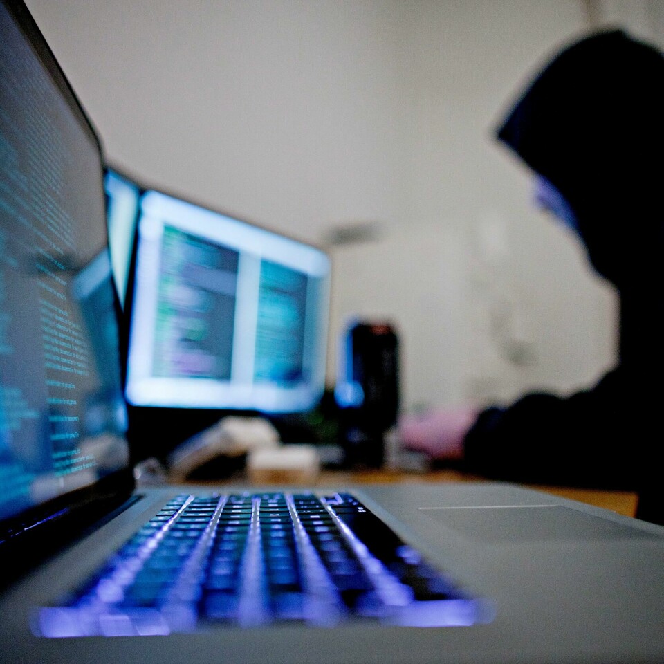 ADVARER: Fem land advarer mot at det kan komme et dataangrep fra Russland om kort tid. Bildet er av en person som sitter ved en pult der det står to datamaskiner. Personen er kledd i hettegenser, og har hetta over hodet. Illustrasjonsfoto: Thomas Winje Øijord / NTB