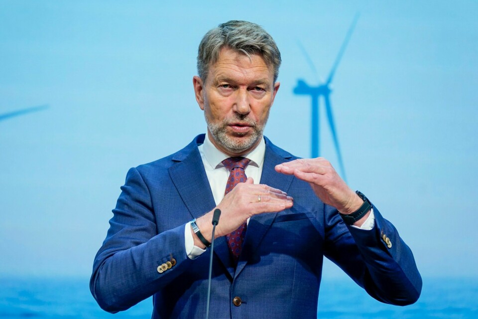 BEHOV: Terje Aasland mener det er behov for å se på hva som kan bli gjort med strømnettet de neste årene. Bildet er av olje- og energiminister Terje Aasland. Han holder hendene opp foran seg, den ene litt høyere enn den andre. De er vannrett. I bakgrunnen er det en skjerm der det er bilde av en vindmølle. Foto: Lise Åserud / NTB
