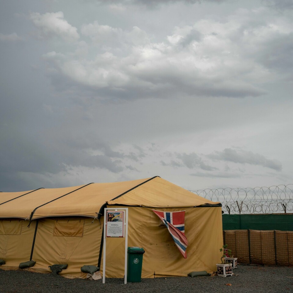 CAMP: Norge har driftet Camp Bifrost i Mali siden 2013. Nå vil regjeringen sende flere soldater dit. Bildet er av et stort sandgult telt. Det er omgitt av høye gjerder med piggtråd på toppen. Det henger et stort norsk flagg på kortsiden av teltet. Dette er en del av Camp Bifrost. Det er overskyet. Foto: Heiko Junge / NTB
