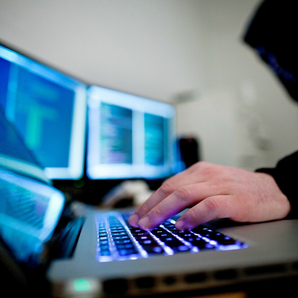 ANGREP: Det er nye dataangrep mot norske nettsider mandag. Bildet er et illustrasjonsfoto av en mann i svart hettegenser som sitter med flere datamaskiner: Thomas Winje Øijord / NTB