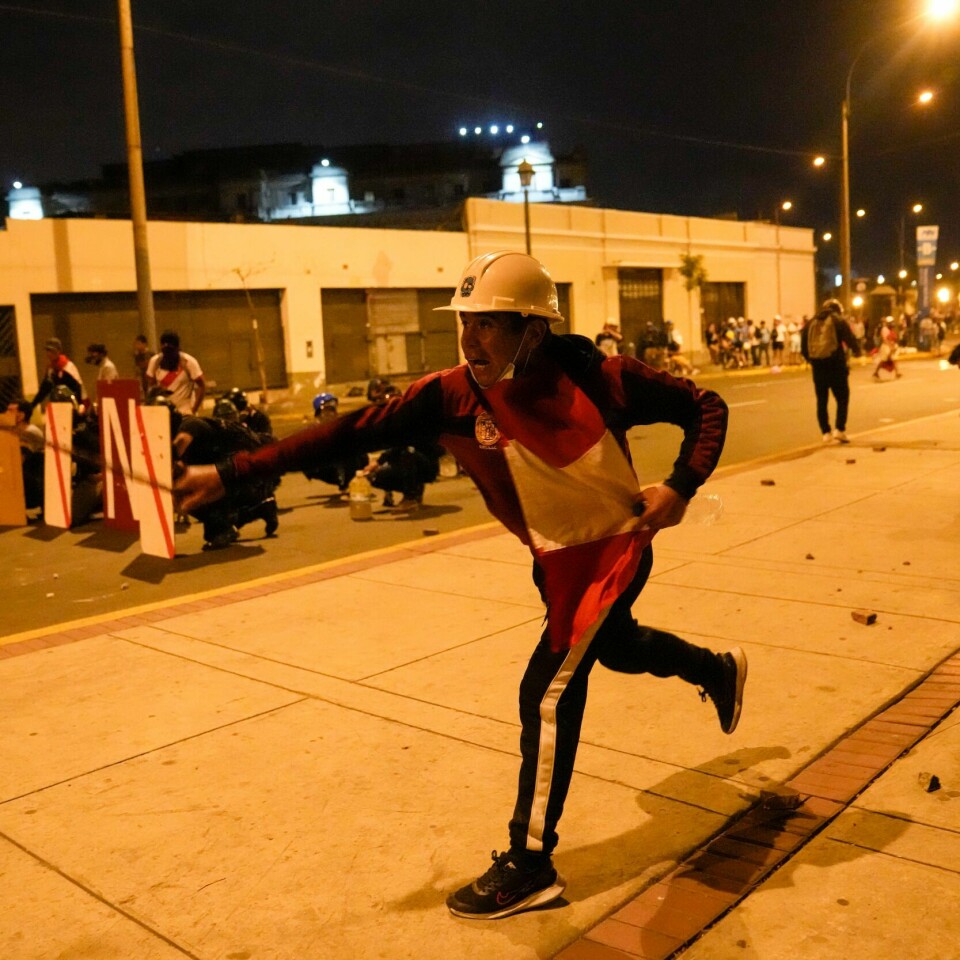 STEINER: Demonstranter kastet stein mot politiet i Lima torsdag. Politiet brukte tåregass mot demonstrantene. Steinkastende demonstranter i Perus hovedstad Lima ble møtt av tåregass fra politiet. Minst 45 personer har mistet livet i den politiske uroen etter at president Dina Boluarte kom til makten i desember. Foto: Martin Mejia / AP / NTB