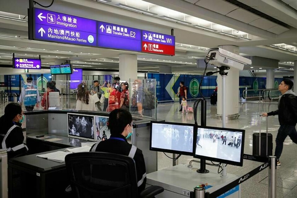 VIRUS: En person leter etter tegn til sykdom blant passasjerer som kommer til flyplassen i Hongkong. Et virus i Kina har ført til frykt for at det skal spre seg.