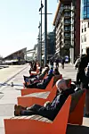 Bildet viser folk som soler seg på benkene på Aker Brygge i Oslo.