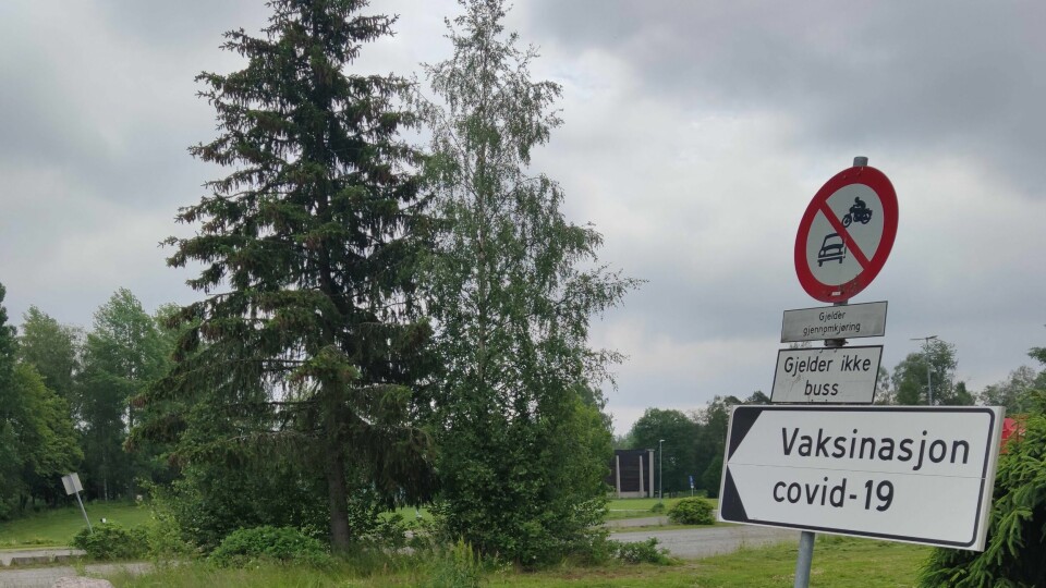 FEIL: Det skjedde en feil da folk ble vaksinert mot korona på Kongsvinger denne uka. Det ble gjort feil i blandingen av vaksinen. Bildet viser skiltingen ned til Holthallen på Kongsvinger. Mellom skiltet og hallen er det en gruslagt parkeringsplass og trær som dekker mye av utsikten ned til hallen. Den er mulig å se til høyre for trærne, og til venstre for skiltet.
