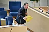 Bildet er av statsminister Stefan Löfven under spørretimen i Riksdagen. Han er framoverlent og holder en gul dokumentmappe. Han er på vei fra plassen i salen og opp på en talerstol foran i salen. Foto: Henrik Montgomery / TT / NTB