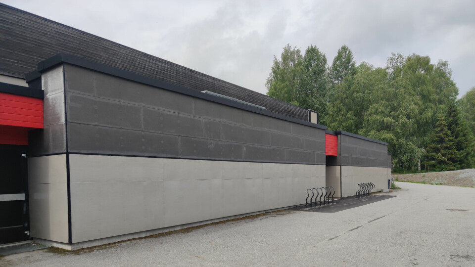 TEST: Sju av 147 som ble vaksinert torsdag fikk bare saltvann. Det gjør at de må bli vaksinert på nytt. Bildet viser fasaden på Holthallen på Kongsvinger. Den er to ulike nyanser av grå, med røde detaljer over inngangene. Det er skog i bakgrunnen.