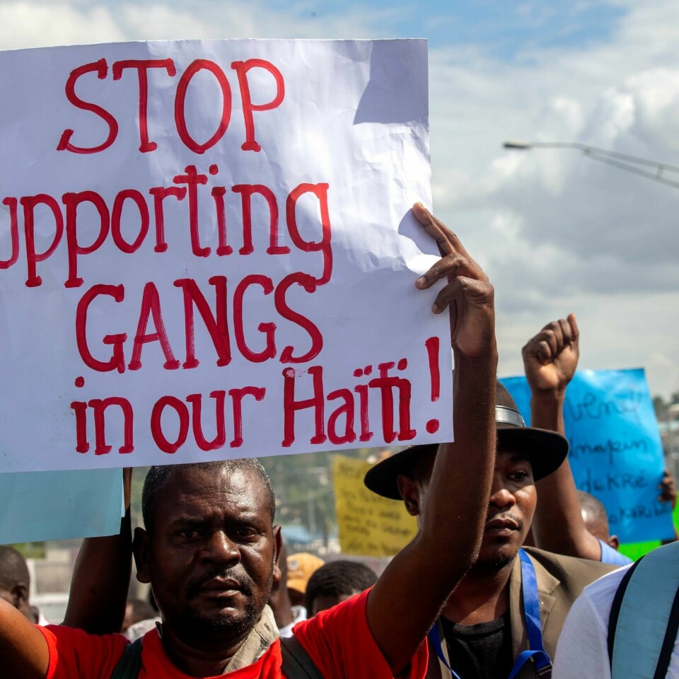 Gjengkriminalitet driver tusenvis av mennesker på flukt. Gjengene kontrollerer store deler av Haiti, og går til angrep på de som demonstrerer mot presidenten. Gjenger og kriminelle grupper dominerer store deler av Haiti, og mange er frustrerte for at ingen står opp mot gjengene. Her holder en demonstrant opp en plakat som oppfordrer folk til å stanse støtten til gjenger. Foto: Dieu Nalio Chery / AP / NTB