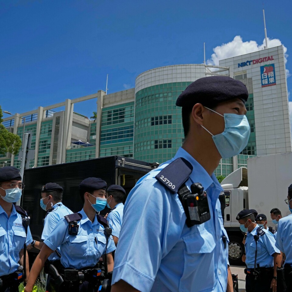 Flere har vært redde for at det ville bli mindre frihet i Hongkong etter at det ble laget en ny sikkerhets-lov. Avisa Apple Daily har vært mot loven. De ble nødt til å stenge, og slutte å lage avis. Bildet er av politi utenfor kontorene til avisa Apple Daily i Hongkong. De har lyseblå uniformer, mørkeblå bereter og lyseblå munnbind. Bildet er fra 17. juni, da sjefredaktøren og fire andre ansatte i avisa ble pågrepet. Foto: Kin Cheung / AP / NTB