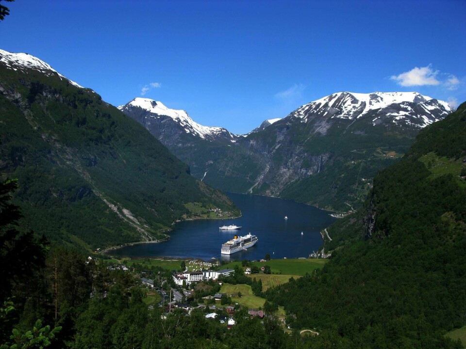 FERIE: Fjord og fjell på Vestlandet tiltrekker turister. Fjord og fjell, Norge på sitt vakreste. Bildet viser et stort skip ligger i fjorden i Geiranger, omkranset av snødekte fjell og blå himmel.Foto: Berit Keilen / NTB scanpix