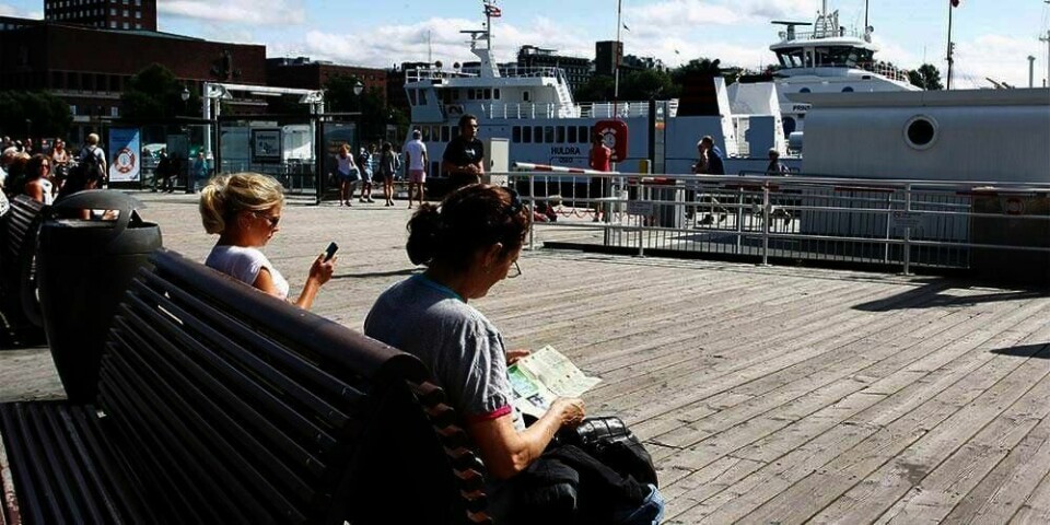 TURIST: En turist sitter på en benk ved Aker Brygge i Oslo. Et kart er godt å ha. Norge er også i år et populært reisemål.
