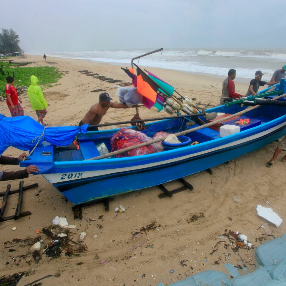 SIKKERHET: Folk bærer en båt. De vil få båten i sikkerhet før stormen Pabuk treffer Thailand fredag kveld.