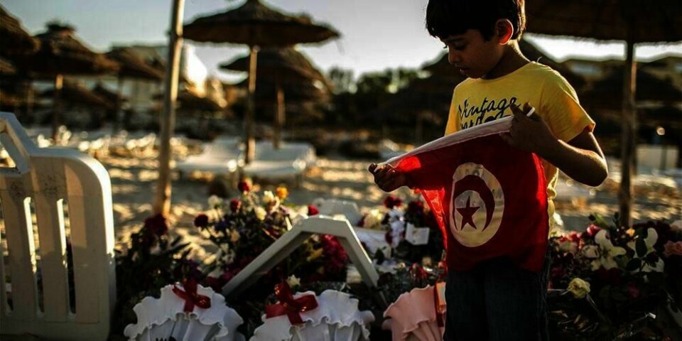 BLOMSTER:  En gutt holder det tunisiske flagget og sørger over de døde. Fredag ble minst 38 mennesker drept i byen Sousse.