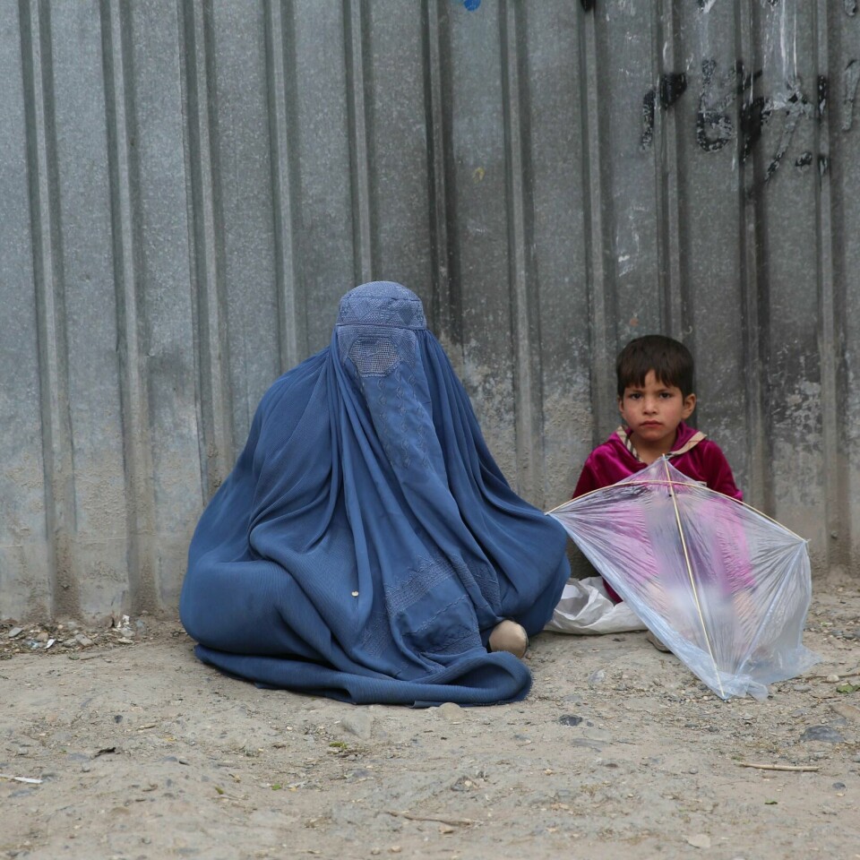 SULT: Hver tredje afghaner er i fare for å sulte. Denne kvinnen og datteren sitter utenfor et bygg og ber om mat eller penger.