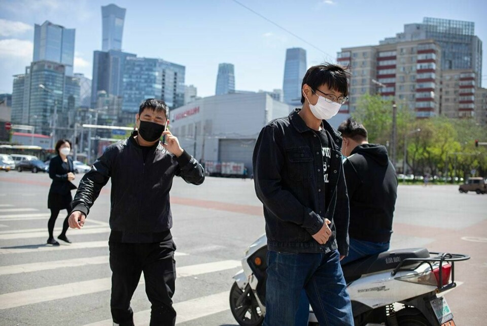 MEDISIN: Bildet viser folk med munnbind i Beijing i Kina. Forskere ved byens universitet har laget en ny medisin. De mener den kan stoppe korona-viruset.