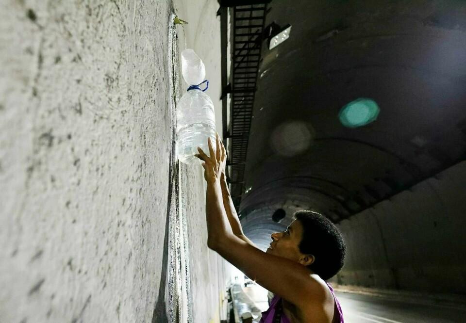VANNMANGEL: En kvinne står i en tunnel og fyller vann på flasken sin. Det er vannmangel i Venezuela som følge av strømbruddene.