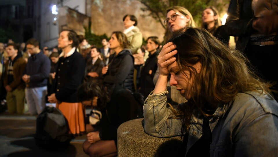 SØRGER: Folk dro til Notre-Dame da den brant. De gråt og sang utenfor. Bilet viser folk som sitter utenfor Notre-Dame.