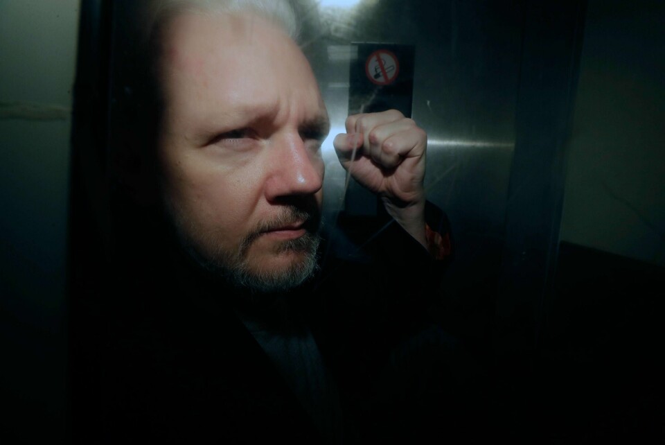TILTALT: Julian Assange løfter knyttneven. Bildet er tatt mens han er på vei fra rettssalen i London. USA har laget en ny tiltale mot ham.