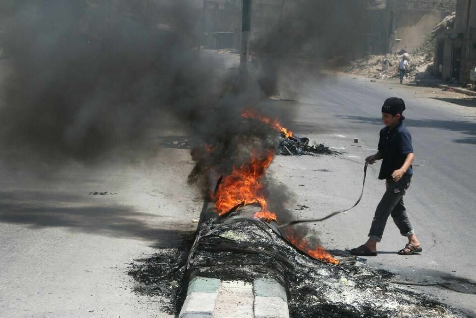 KRIG: En gutt i Aleppo setter fyr på bildekk. Da blir det vanskeligere for de syriske flyene å slippe bomber.