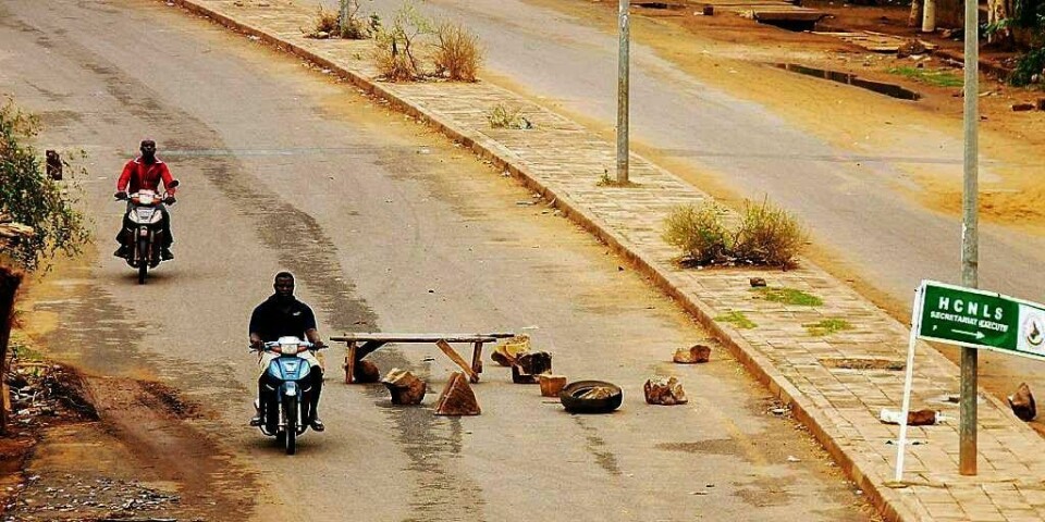 KRISE: Motorsyklister kjører gjennom øde gater med veisperringer i Malis hovedstad Bamako. Amnesty International melder om store brudd på menneske-rettighetene i landet.
