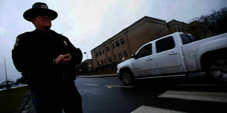 MASSAKRE: En politimann passer på før et møte om våpen i Newtown i USA i desember. 26 personer ble drept da Adam Lanza begynte å skyte på barneskolen i byen.
