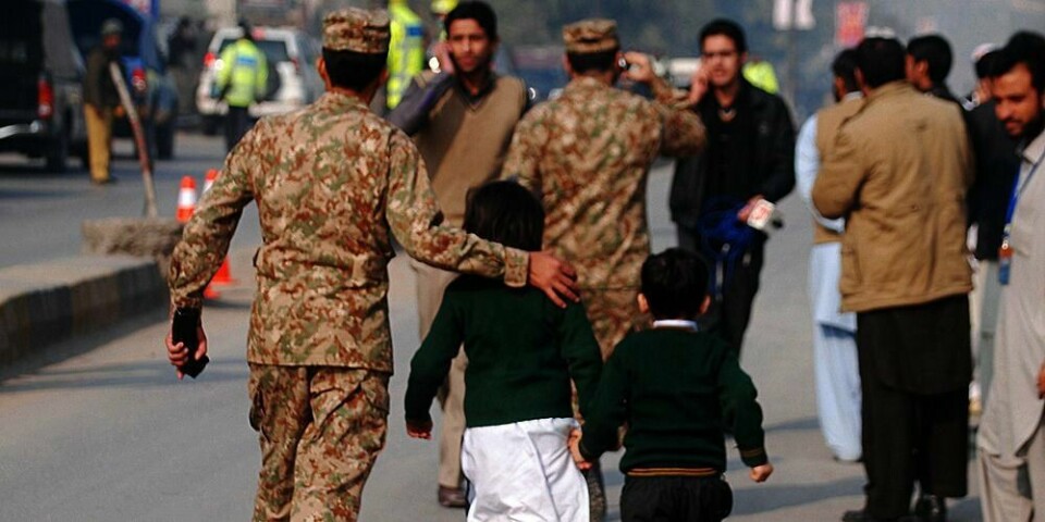 ANGREP: En soldat hjelper to barn i sikkerhet. Terrorgruppa Taliban har angrepet en skole i Pakistan.