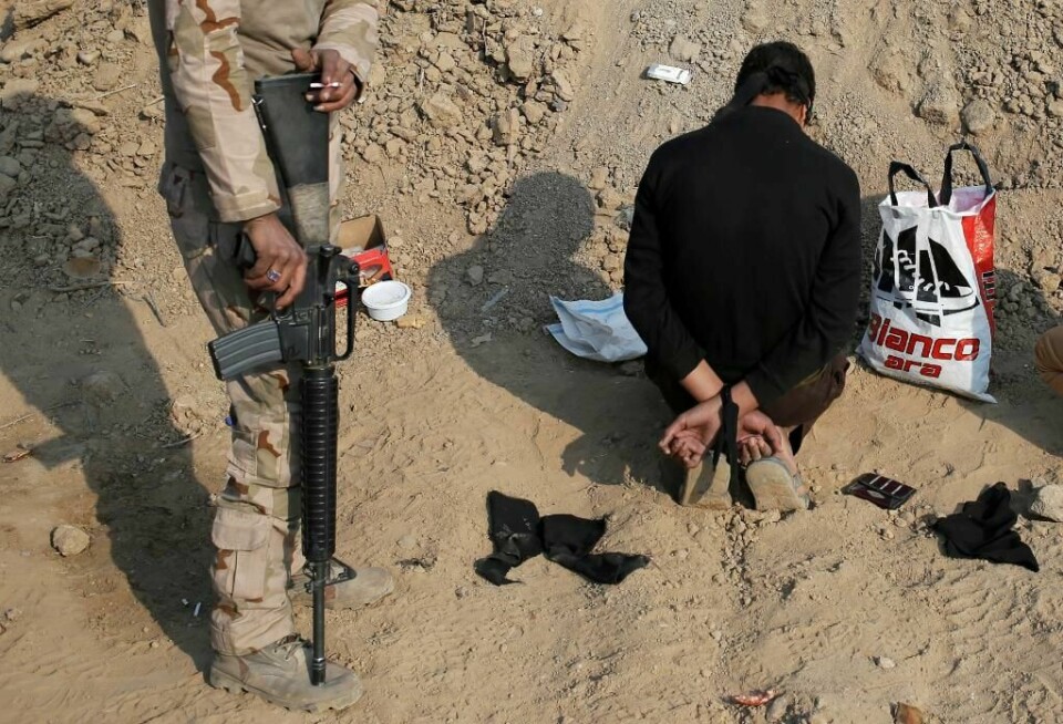 VOKTER: Soldater vokter byen Mosul. Noen menn blir anklaget for å støtte terrorgruppa IS. Her passer en soldat fra Irak på en mann. Han kan være en IS-kriger.