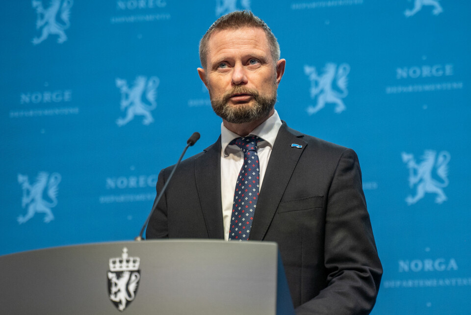 NYTT: Bildet er av helseminister Bent Høie. Han står bak en grå talerstol og har på seg en mørk dress. Han står foran en blå vegg. Foto: Ali Zare / NTB